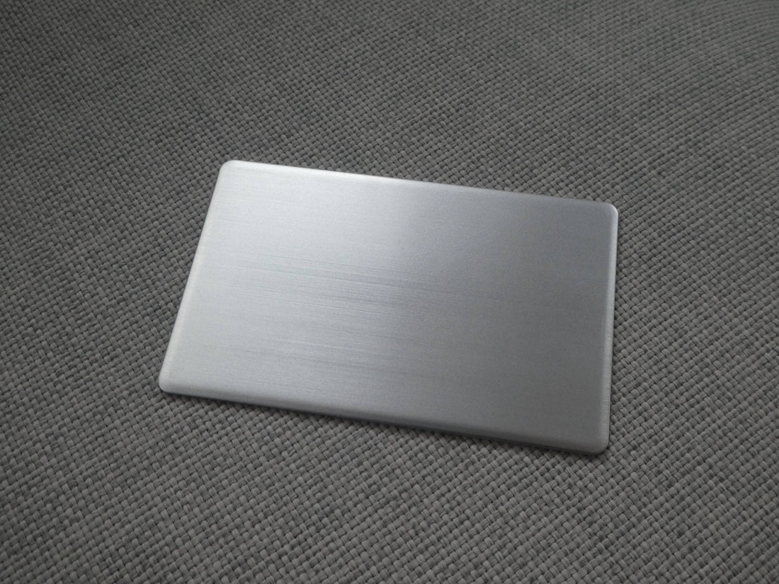 a premium metal business card, showing its sleek, smoothed edges and subtle brushed reflection.