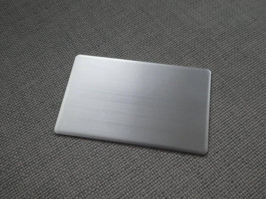 a premium metal business card, showing its sleek, smoothed edges and subtle brushed reflection.